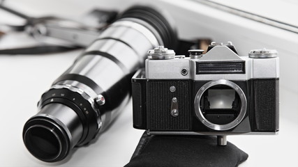 Old photo equipment - vintage SLR film camera body with large lens b/w contrast image