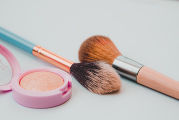 make up brushes and highlighter with scrunchie on a white background