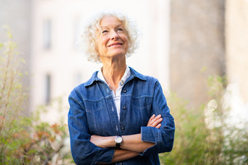 attractive older woman standing outside with arms crossed