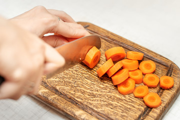 Cutting carrots and other vegetables with a kitchen knife on a wooden Board