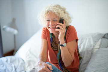 attractive old woman sitting at home using mobile phone