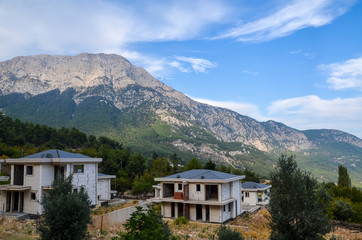 Fototapeta na wymiar Unfinished houses with mountain background behind with clouds on the sky, Turkey