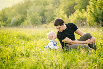 Fototapeta premium Father's day. A man and his daughter enjoy a vacation in a green park or forest in the warm rays of the sun, experiencing family joy.