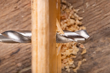 Drilling in a piece of wood with a metal drill bit. Small carpentry work in a home workshop.