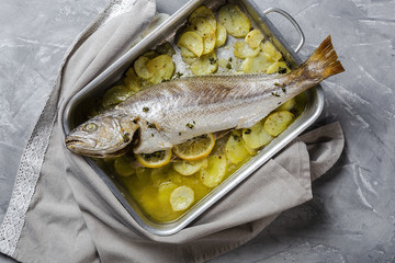 Fresh raw sea bass fish prepared for roasting with potatoes