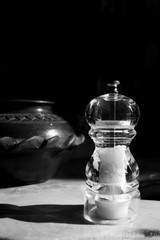Obraz na płótnie Canvas Classy transparent salt grinder with a clay pot in the background shot in black and white