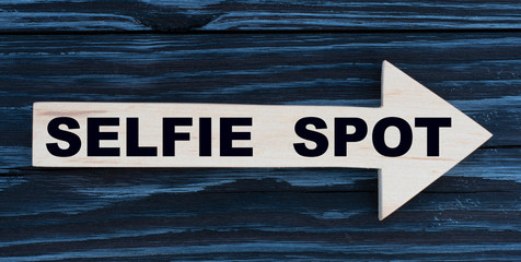 SELFIE SPOT word written on a wooden arrow on a beautiful dark background