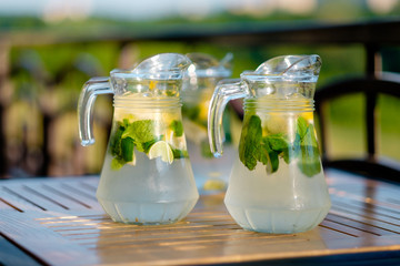 fresh lemon juice with mint in the open air in outdoor cafe with green background in sunlight