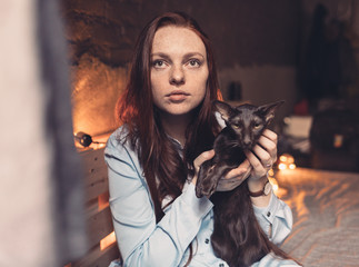 Red-haired girl sitting with a cat by the window