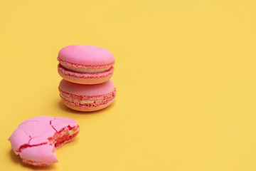 Stack of pink macaroons on yellow background. Colorful almond cookies