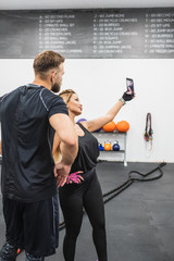 chica atractiva haciéndose foto con su entrenador personal