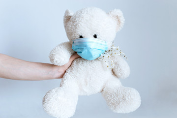 soft toy in the hands of a man with a medical mask on a white background