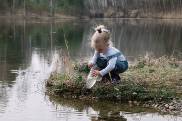 Fototapeta na wymiar Little girl catches and feeds fish