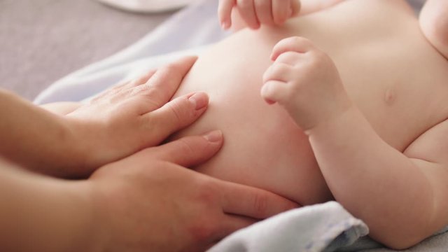 Mother massaging baby tummy. Baby skin care and development concept.