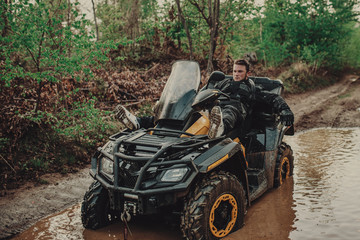 A young man in a white helmet rides through the woods on a Quad bike. Extreme hobby. A trip to ATV on the road from logs. Quad Biking through the forest.