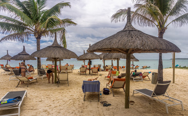 Straw huts and relaxation chairs on the beach of a tropical resort in the island of Mauritius