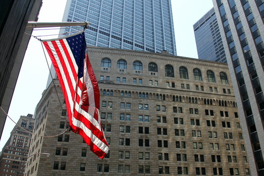 US Flag flying on the background of the facade of the Federal Reserve building in New York - July 12, 2012
