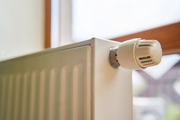 Radiator in the apartment. White heated battery. Thermostat head of a heating radiator in an apartment, office.