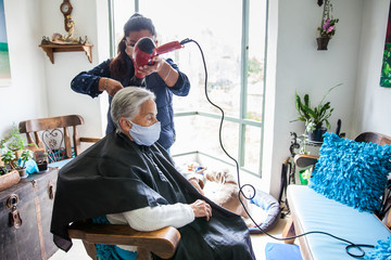 Senior woman getting a haircut at home during Covid-19 pandemic wearing face mask