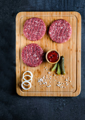 Fototapeta na wymiar Red burger meat closeup on black background. Top view. Food preparation.