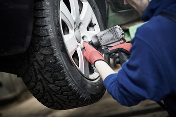 Auto service. Worker screwdriving an automobile wheel. Break maintenance or tyre replace