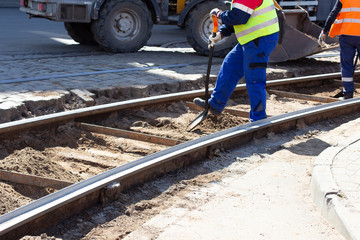 Worker with shovel digs at replacement tram rail