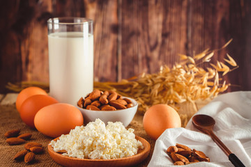Rustic protein balanced diet food. Cottage cheese, eggs, nuts and milk on a wooden background.