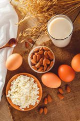 Rustic protein balanced diet food. Cottage cheese, eggs, nuts and milk on a wooden background.