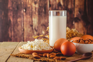 Rustic protein balanced diet food. Cottage cheese, eggs, nuts and milk on a wooden background.