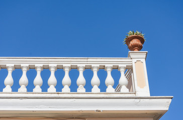 Neoclassical architecture with balusters and a flower pot against the blue sky