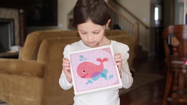 Little Girl Showing Artwork on a Diamond Painting Kit. Hand held video as happy girl hold her self-made artwork.