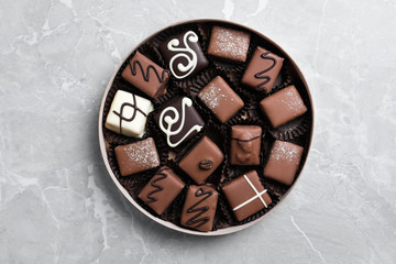 Box with tasty chocolate candies on light grey marble table, top view