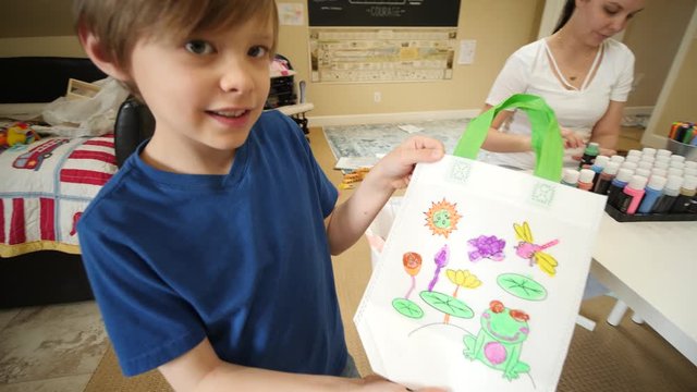 Young Kid Showing His Artwork on The Antistress Coloring Bag. Happy boy has finished his hand made work and shows it to the camera.
