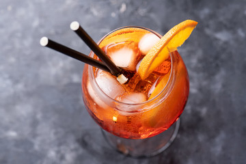 Classic italian aperitif aperol spritz cocktail in glass with ice cubes and with slice of orange on dark background, traditional summer fresh drink, close up and top view