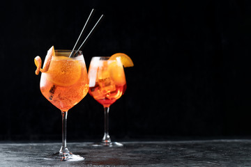 Two glasses of classic italian aperitif aperol spritz cocktail with slice of orange on dark background, traditional summer fresh drink, copy space - obrazy, fototapety, plakaty
