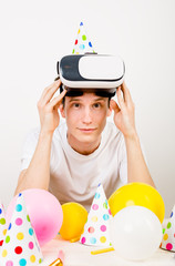 an attractive moldovan man wearing a white T-shirt lifting a VR helmet above the eyes of a sopkoyno...