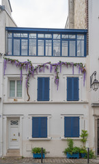 Fototapeta premium Paris, France - 05 09 2020: Montmartre district. House facade with blue shutters and wisteria branch during confinement against coronavirus