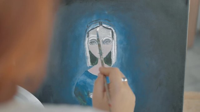 pintora retoca con pincel de &oacute;leo un cuadro visto de cerca