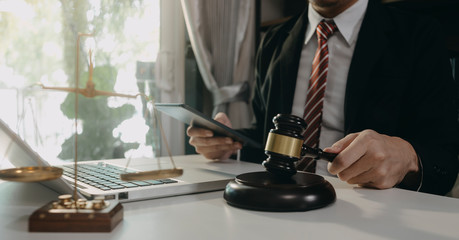 Justice and law concept.Male judge in a courtroom with the gavel, working with, computer and docking keyboard, eyeglasses, on table in morning ligh