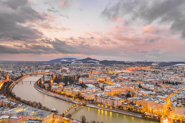 Aerial drone view of north Salzburg and mirabelle park by Salzach river in snowy winter during sunset hour