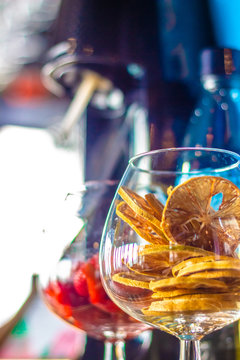 A glass full of dried lemons standing on a bar counter ready to be made into a cocktail drink at a party