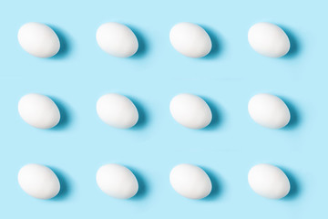 Poultry products. Pattern of white chicken eggs on a blue background.