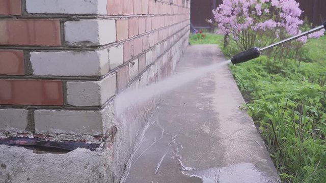 Outdoor floor cleaning with high pressure water jet. care of a country house.