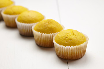 Muffins on white wooden table, selective focus. Row of cupcakes