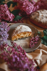 Homemade Apple pie on a wooden table next to a bowl of lilacs. Gentle toning.