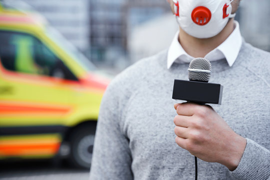 News Reporter Wearing A Prevention Mask And Speaking Into A Microphone