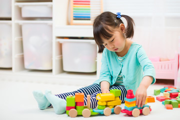 toddler girl playing creative toy blocks at home against white background