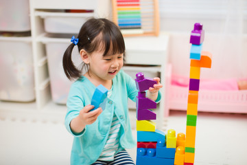 toddler girl playing creative toy blocks at home against white background