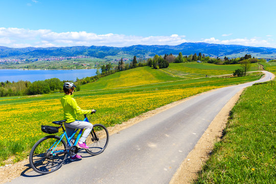 Woman cycling around Czorsztynskie lake near Falsztyn village on sunny spring day, Pieniny Mountains, Poland