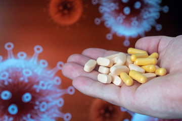 Pills in a man’s hand against the background of the image of a coronavirus. Healthcare concept.